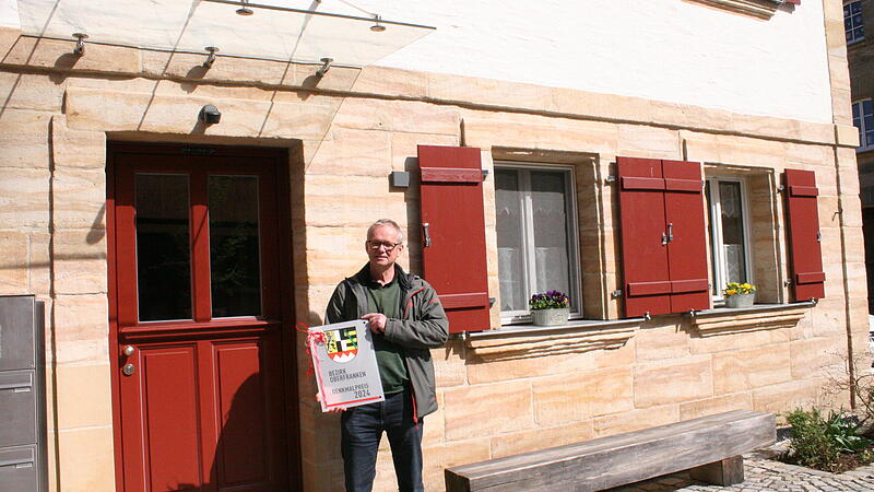 Der geb&uuml;rtige Pinzberger Edwin Stirnwei&szlig; mit dem Denkmalschutzpreis des Bezirks Oberfranken vor seinem renovierten Haus.
