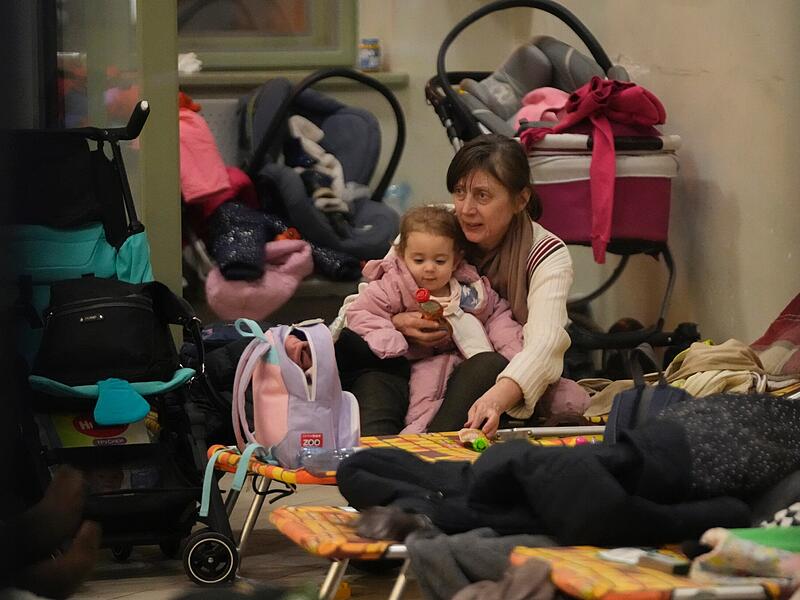 Eine Frau und ein Kind, die aus der Ukraine geflohen sind, sitzen neben einem Kinderbett in einem Schutzraum f&uuml;r Frauen und Kinder am Bahnhof in Przemysl. Seit Beginn der russischen Invasion in die Ukraine sind nach Angaben der Vereinten Nationen bereits eine Million Menschen aus dem angegriffenen Land geflohen.