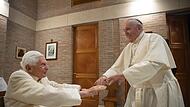 Papst Franziskus (rechts) gibt nach dem Konsortium 2020 dem emeritierten Papst Benedikt XVI. bei einem Besuch mit den ernannten Kardinälen die Hand.