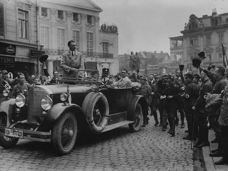 Adolf Hitler wird bei seiner Ankunft in Weimar von SA-M&auml;nnern begr&uuml;&szlig;t. Im Fond des Wagens Rudolf He&szlig; &ndash; Aufnahme vom 03./04.07.1926