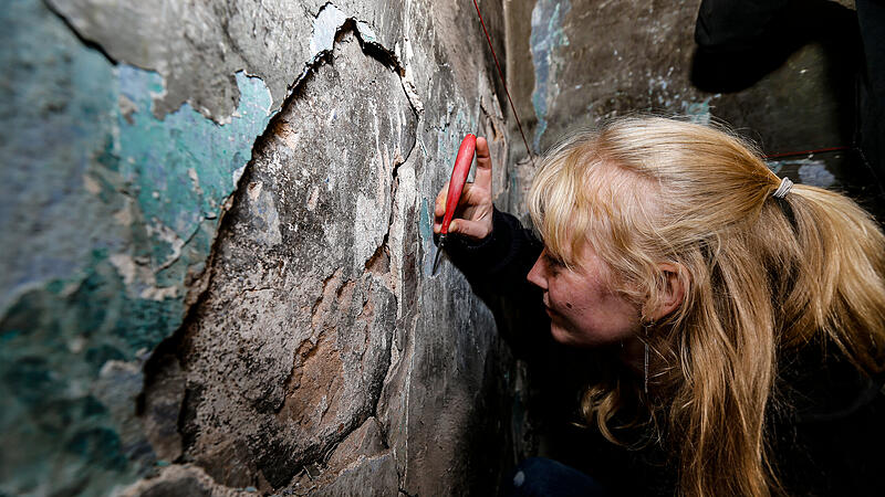Eine Studierende untersucht eine Wand im kleinsten Haus in Bamberg genau. Unter dem Putz kommt Geschichte zum Vorschein.