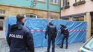 Polizeibeamte beim Errichten eines Sichtschutzes aus blauer Folie an dem Blumengeschäft