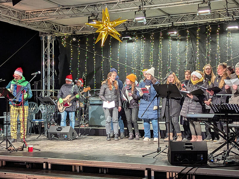 Die beiden Ch&ouml;re &bdquo;Close Harmony & Herzt&ouml;ne&ldquo; verbreiteten Weihnachtsstimmung und animierten zum Mitsingen. Links: David Saam, der musikalische Leiter des Weihnachtssingens.
