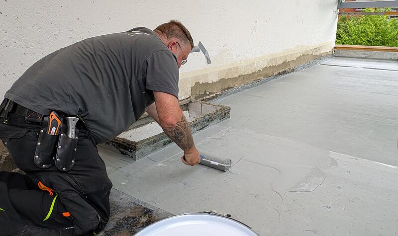 Mirko K&ouml;hler von EFT Eschenbacher Flachdachtechnik bringt mit einer Rolle Kemperol auf, um die Terrasse an der Kulmbacher Wolfskehle gegen Wasser abzudichten.