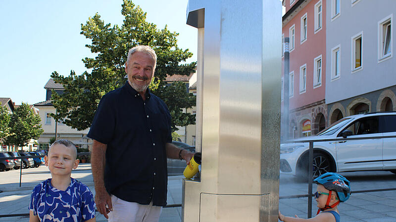 Oberbürgermeister Frank Rebhan testet die neue Trinkwasser- und Nebelsäule am Marktplatz.