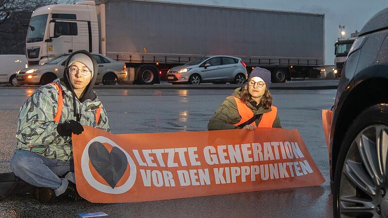 Aktivisten  der „Letzten Generation“ blockieren eine Straße.