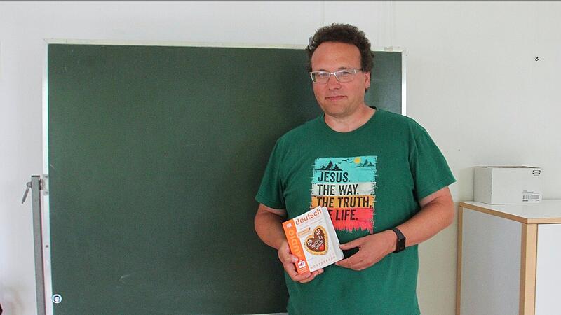 Pfarrer Martin Hild steht vor einer Tafel in einem Raum in der evangelischen Kirche.