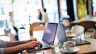 Ein Mensch arbeitet an seinem Computer in einem Café Ein Mensch arbeitet an seinem Computer in einem Café