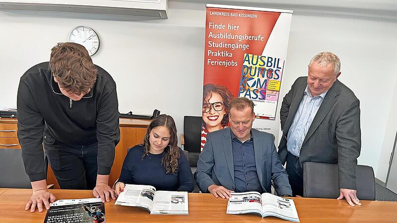 Die Auszubildenden (von links) Nikolas Tiefenbach und Zoe Grom aus dem ersten Lehrjahr sichten gemeinsam mit Frank Bernhard (Wirtschaftsförderung im Landratsamt Bad Kissingen) und Landrat Thomas Bold den neuen Ausbildungskompass.