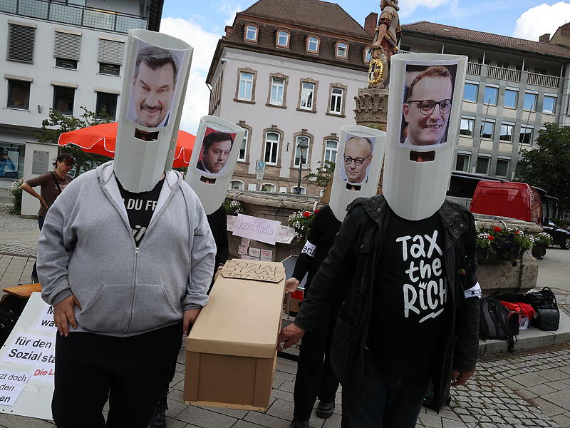 Die Linke zelebrierte am Holzmarkt das Begr&auml;bnis des Sozialstaates und setzten sich Masken mit den Konterfeis von Bundeskanzler Friedrich Merz, Bayerns Ministerpr&auml;sident Markus S&ouml;der, CDU/CSU-Fraktionschef Jens Spahn und Bundesfinanzminister Lars Klingbeil auf.
