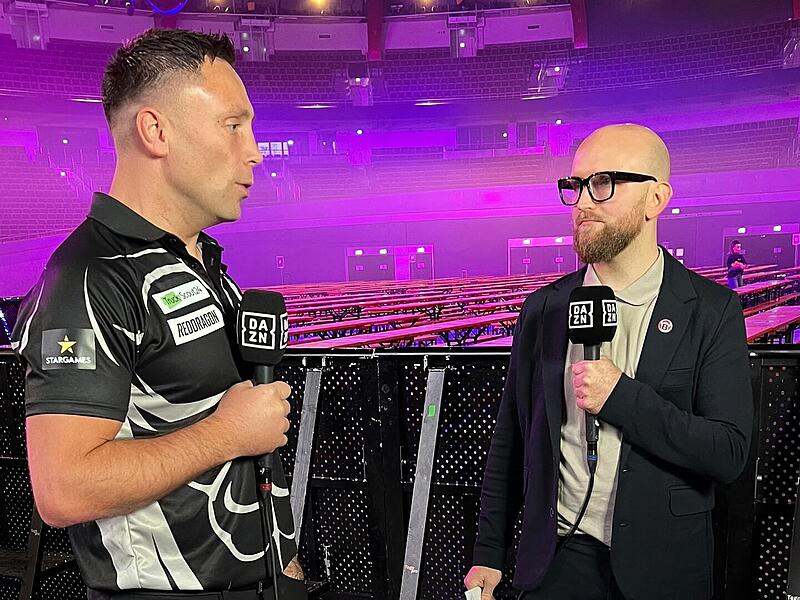 Nah dran an den Stars: Adrian Geiler (rechts) begleitet f&uuml;r Dazn den Dartsport, bekommt die Topstars wie Gerwyn Price regelm&auml;&szlig;ig ans Mikrofon.