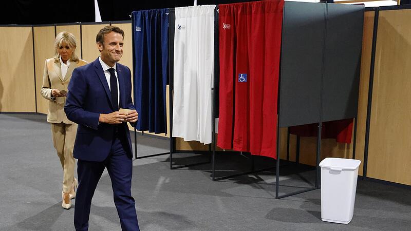 Emmanuel Macron, Präsident von Frankreich, und seine Frau Brigitte verlassen in Paris die Wahlkabine, bevor sie ihre Stimmen in der ersten Runde der französischen Parlamentswahl abgeben.