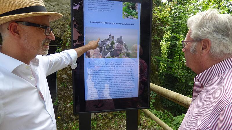 Archäologe und Mittelalterhistoriker Jochen Scherbaum (l.) erklärt den Eröffnungsgästen in Streitberg die Stele mit der 3 D-Ansicht der Streitburg vor dem Lochgefängnis.