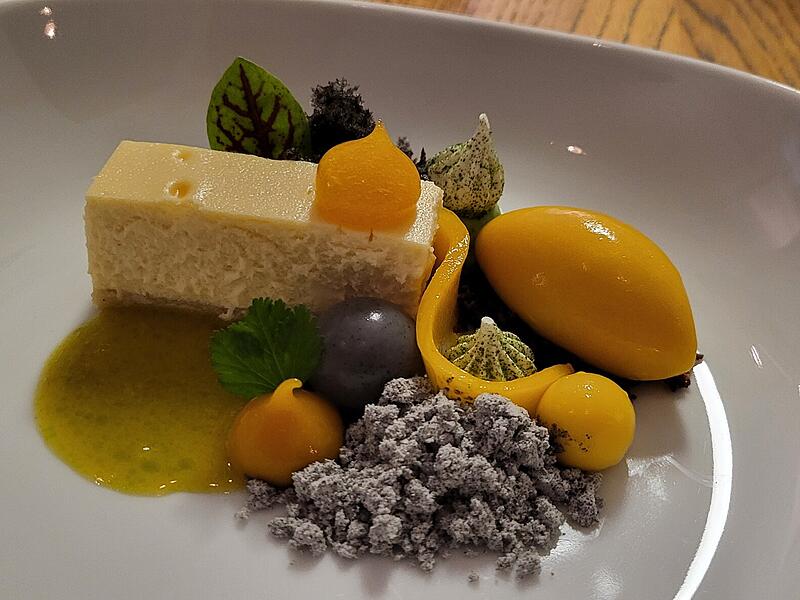Das fertig angerichtete Pre Dessert mit dem umkämpften Cheesecake in der Mitte. Garniert mit Mango, Sesam, Frischkäse und Koriander.