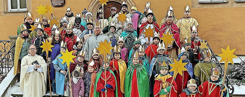 Die Sternsinger von Ebern nach dem Gottesdienst auf der Treppe zur Stadtb&uuml;cherei mit Pfarrer Gregor Sauer (v.l.).