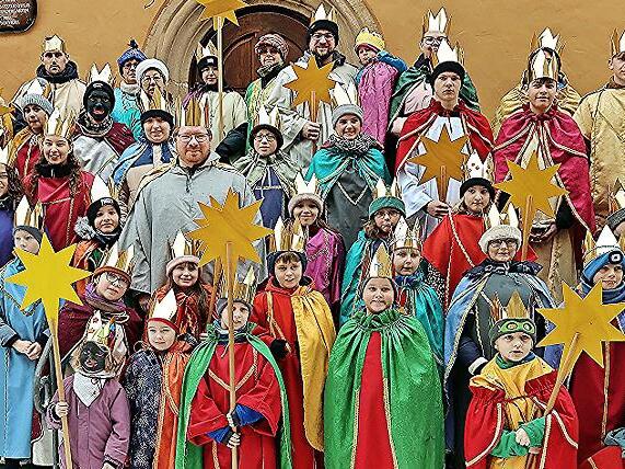 Die Sternsinger von Ebern nach dem Gottesdienst auf der Treppe zur Stadtb&uuml;cherei mit Pfarrer Gregor Sauer (v.l.).