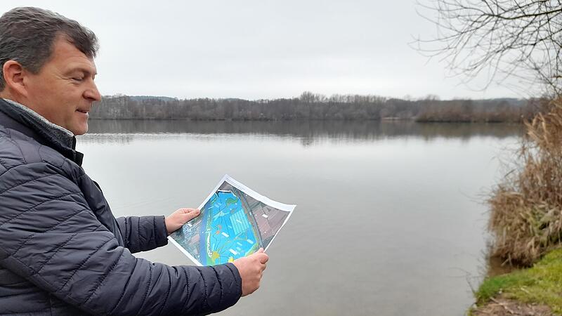 In diesem Bereich am Baggersee, Blick von der Oberhaider Seite aus, soll eine schwimmende Photovoltaikanlage entstehen, zeigt B&uuml;rgermeister Carsten Joneitis.