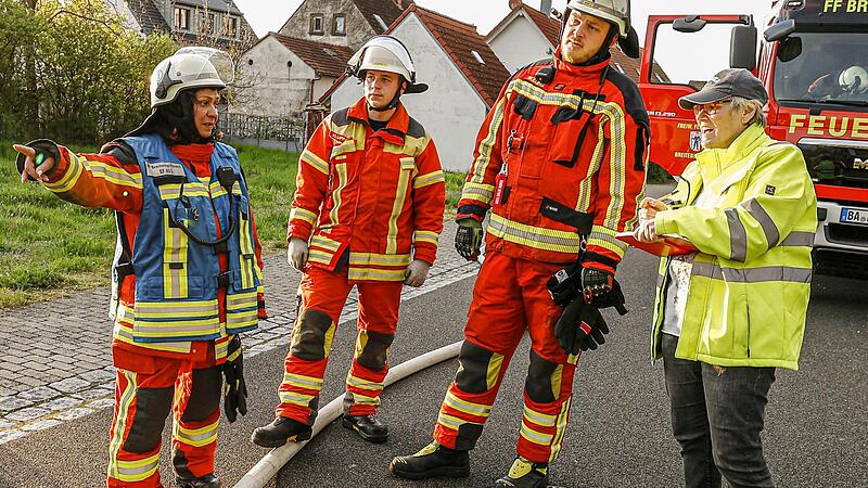 Kreisbrandmeisterin Monika Schramm (links) erklärt Teilnehmern aus der Feuerwehr Breitengüßbach, worauf es bei der Übung gerade ankommt. FT-Reporterin Anette Schreiber (rechts) verfolgt das Geschehen aus nächster Nähe.