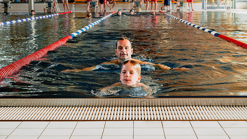 Konzentriert schwimmt der siebenj&auml;hrige Constantin Sack seine Bahn f&uuml;r das Deutsche Schwimmabzeichen in Bronze. Direkt hinter ihm folgt sein Vater Andr&eacute;. Im Hintergrund verfolgen weitere Teilnehmer und Pr&uuml;fer das Geschehen im Hallenbad des K&ouml;nigsbads in Forchheim.