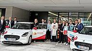 Mitarbeiter und Gäste bei der Fahrzeugübergabe.