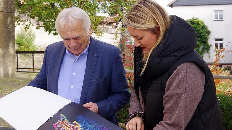 Hartmut Nenninger bl&auml;ttert mit Kronachs Pressesprecherin, Sophia Raithel, im neuen Kunstkalender.