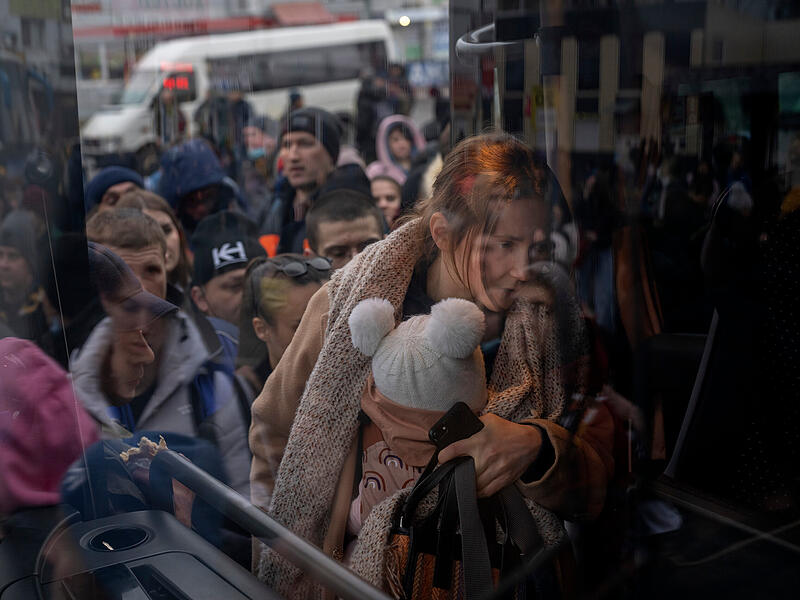 Eine Frau hält ihr Baby im Arm, während sie in einen Bus steigt, der Kiew verlässt. Russische Truppen haben ihren erwarteten Angriff auf die Ukraine gestartet.