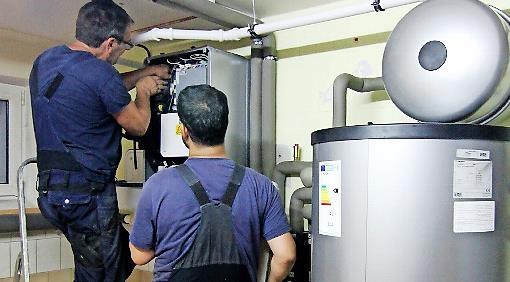 Zwei Techniker stellen eine W&auml;rmepumpe ein. Im Landkreis informiert der Verein Energiewende ER(H)langen &uuml;ber diese Heizungstechnik.