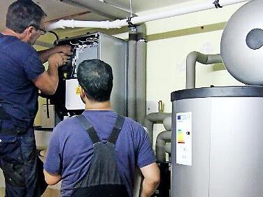 Zwei Techniker stellen eine W&auml;rmepumpe ein. Im Landkreis informiert der Verein Energiewende ER(H)langen &uuml;ber diese Heizungstechnik.