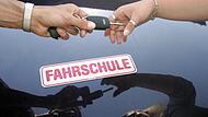 Ein Fahrlehrer überreicht seiner Fahrschülerin den Schlüssel zum Fahrzeug.