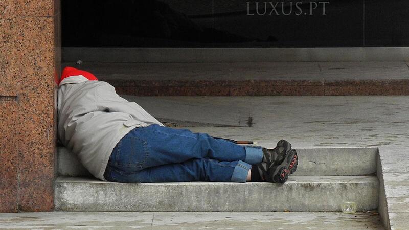 Ein Obdachloser liegt auf einer Treppe und schl&auml;ft.