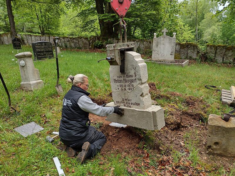 Denise Ullrich von der Firma Ullrich Naturstein Design setzt den Grabstein von Anton Hergert auf dem Friedhof von Altglash&uuml;tten wieder ein.