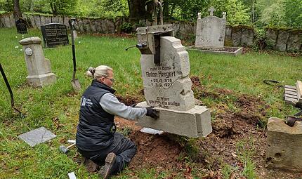Denise Ullrich von der Firma Ullrich Naturstein Design setzt den Grabstein von Anton Hergert auf dem Friedhof von Altglash&uuml;tten wieder ein.