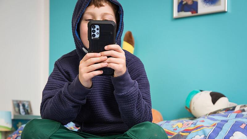 Kind h&auml;lt Smartphone in den H&auml;nden