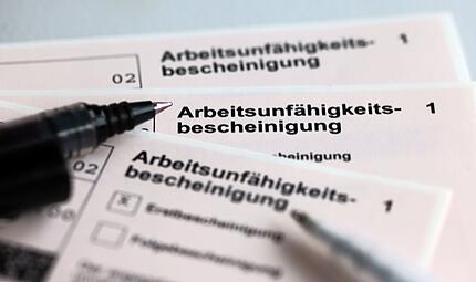 Stifte liegen auf Arbeitsunf&auml;higkeitsbescheinigungen
