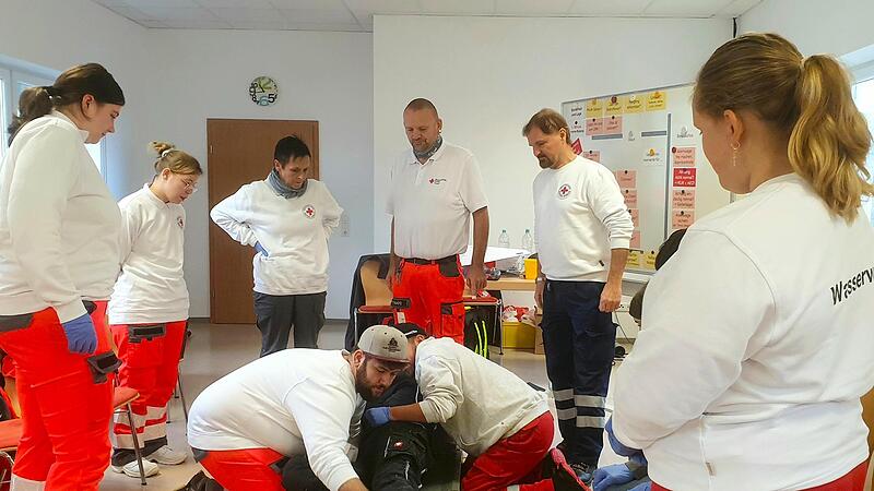 BRK-Instruktor Rudolf Hanika (rechts, stehend) und Ausbilder Stefan Sch&uuml;tz (mittig, stehend) f&uuml;hrten eine Unterweisung in der Durchf&uuml;hrung der richtigen Lagerungstechnik auf einer Trage durch.