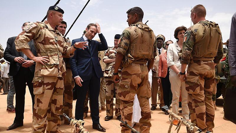 Emmanuel Macron (Mitte l), Pr&auml;sident von Frankreich, steht zwischen Soldaten w&auml;hrend eines Besuchs bei den Truppen der Operation &bdquo;Barkhane&ldquo;, Frankreichs gr&ouml;&szlig;ter ausl&auml;ndischer Milit&auml;roperation, im Norden Malis.