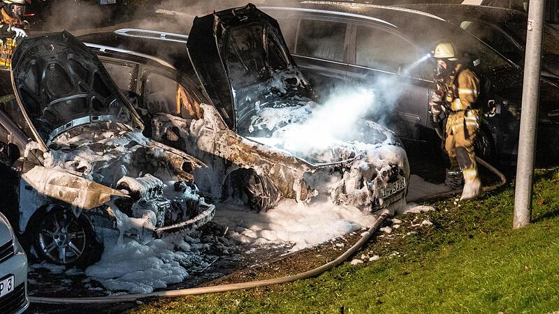 Feuerwehrleute beim L&ouml;schen der beiden Autos auf dem Parkplatz der Lichtenfelser Berufsschule.