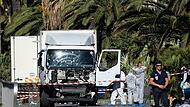 Polizisten stehen um den Lastwagen, mit dem der Attentäter beim Anschlag in Nizza in eine Menschenmenge an der Strandpromenade gerast war.