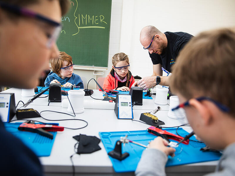 Niklas L&ouml;ffler zeigt den kleinen Bastlern, wie man l&ouml;tet. NEO ist ein Kreativ- und Technologiezentrum f&uuml;r Kinder und Jugendliche in Bamberg. Hier finden Kurse zur Vermittlung von Technikwissen statt.