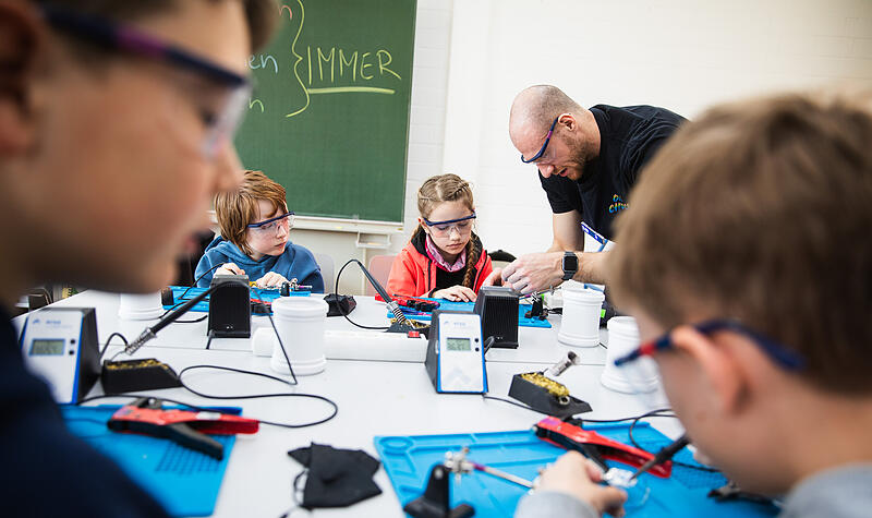 Niklas L&ouml;ffler zeigt den kleinen Bastlern, wie man l&ouml;tet. NEO ist ein Kreativ- und Technologiezentrum f&uuml;r Kinder und Jugendliche in Bamberg. Hier finden Kurse zur Vermittlung von Technikwissen statt.