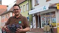 B&auml;cker Maximilian Ley h&auml;lt vor seinem Gesch&auml;ft am Marktplatz in Schl&uuml;sselfeld eine Sch&uuml;ssel gef&uuml;llt mit Zwetschgen in seinen H&auml;nden.