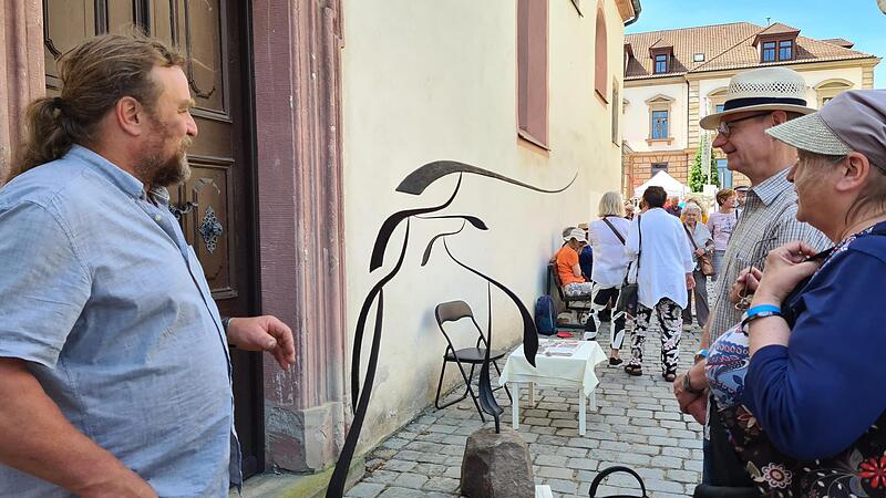Sandro Dorst zeigt einem erstaunten Ehepaar ein Windspiel aus Metall.Forchheim & Fr&auml;nkische Schweiz