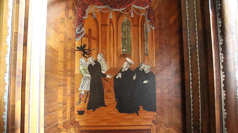 Die Holztafeln des Banzer M&ouml;nchschores sind mit Intarsien aus Zinn, Horn, Perlmutt, Elfenbein und Schildpatt verziert, die Szenen aus dem Leben des Heiligen Benedikt zeigen. Die Gew&auml;nder der Figuren sind zumeist aus schwarz gef&auml;rbtem Birnbaumfurni...