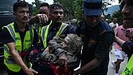 Rescuers carry in their arms a flood survivor, following flash floods and a landslide disaster in Devghat, in the Nepal's Nuwakot district on August 26, 2026. A massive flood and landslide disaster on the Nepal-Tibet border killed at least 103 people on August 26, 2026 and left several hundred missing, many of them foreign tourists. Aid workers said entire settlements had been "wiped out". Some 403 tourists -- 341 of them foreigners -- were unaccounted for several hours after the disaster struck, according to the tourism ministry. (Photo by PRAKASH MATHEMA / AFP)