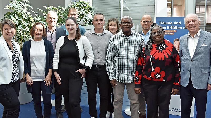 Die Bankfamilie begr&uuml;&szlig;t den ehemaligen Praktikanten Gabriel Nsah. Vorn (v.l.): Carola Huberth, Marion Fett, Tamara Lober, Lars Schrettenbrunner, Gabriel und Ehefrau Anna Nsah, Alfons Trautner. Hinten (v.l.): Reinhold Bakof, Laurenz Kraus, Simone K...