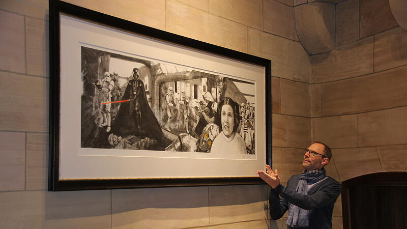 Das Herzst&uuml;ck der Ausstellung: Mit Rahmen &uuml;ber zwei Meter breit thront die Collage der Tantive-IV-Erst&uuml;rmung im Hauptsaal. Bereits seit 2022. Allein der Rahmen und die Verglasung haben 4000 Euro gekostet. Daneben steht Stephan Zipfel, der als Kurator an der Ausstellung beteiligt ist.