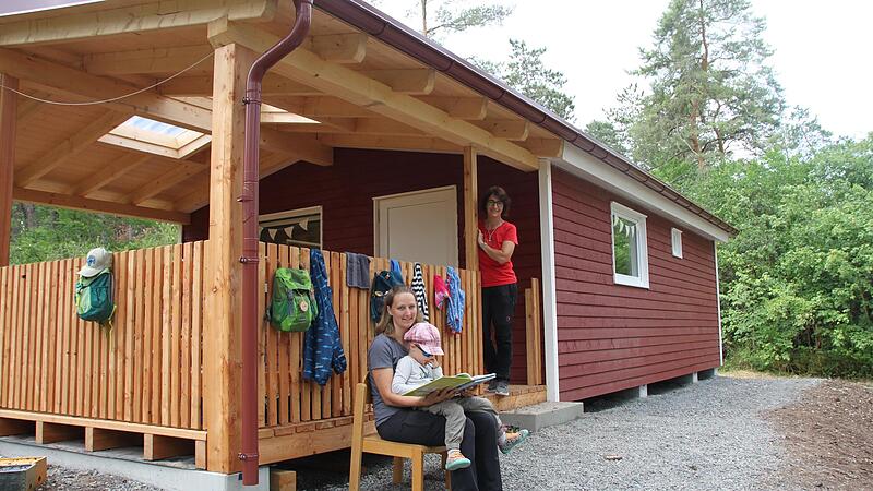 Erzieherin Petra Schlereth (vorne) liest einem der M&auml;dchen vor der neuen H&uuml;tte aus einem Buch vor. Im Hintergrund h&ouml;rt Gesch&auml;ftsf&uuml;hrerin Kerstin Augsburg zu.
