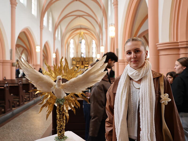 „Der trügerische Glanz“ nennt Annika Demmert ihr Werk. Eine weiße Taube, das universelle Friedenssymbol, steigt aus einem goldenen Kranz voller Flammen hervor: Doch die Kritik erschließt sich den Betrachtern von der anderen Seite. Denn in der Taube steckt ein Dolch in Kreuzform.
