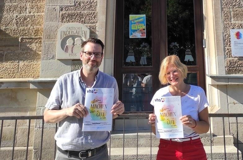 Florian Schmitt, Geschäftsführer und Renate Knaut, Pädagogische Leiterin, vor dem vhs-Standort Bad Königshofen, mit einem druckfrischen Programmheft.