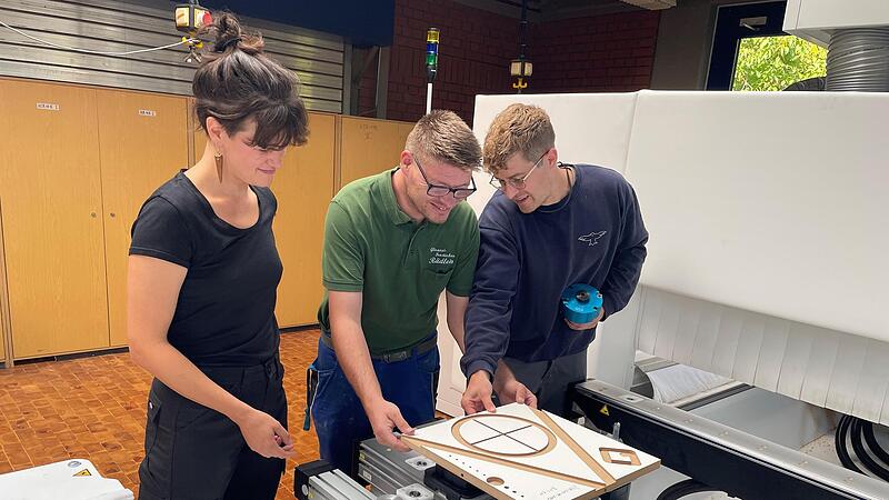 ntegra-Mitarbeiter Timmy Krenz (Bildmitte) l&auml;sst sich zum &bdquo;Gehilfen im Baugewerbe&ldquo; ausbilden. Hier hat er sich  von Bamberger Berufssch&uuml;lern Marlene Peter und Thomas Schell schon einmal die F&uuml;nf-Achs-Fr&auml;smaschine zeigen lassen.